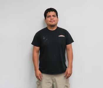 Male employee Chris Moldanado standing in front of a muted wall.