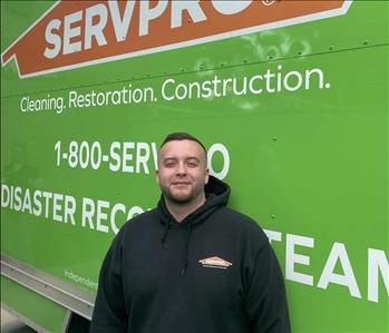 Male employee Tyler Dailey standing in front of a SERVPRO vehicle