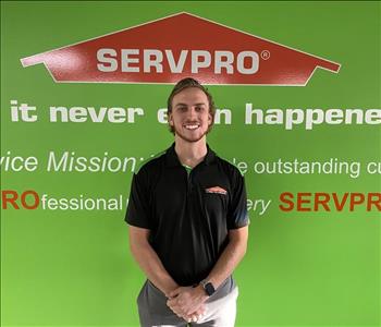 Male employee Mason Grossnickle standing in front of a green wall with the SERVPRO mission statement
