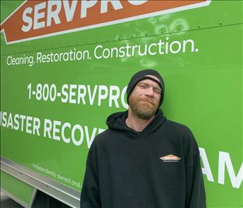 Male employee John Minter standing in front of a SERVPRO vehicle