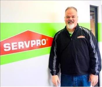 Keith Whalen standing in front of a wall with the SERVPRO logo on it