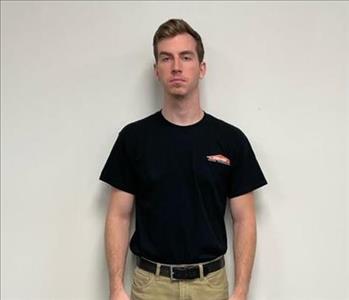 Male employee Chris Via standing in front of a muted wall.