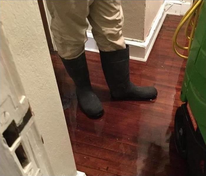 A person wearing rain boots in their flooded home
